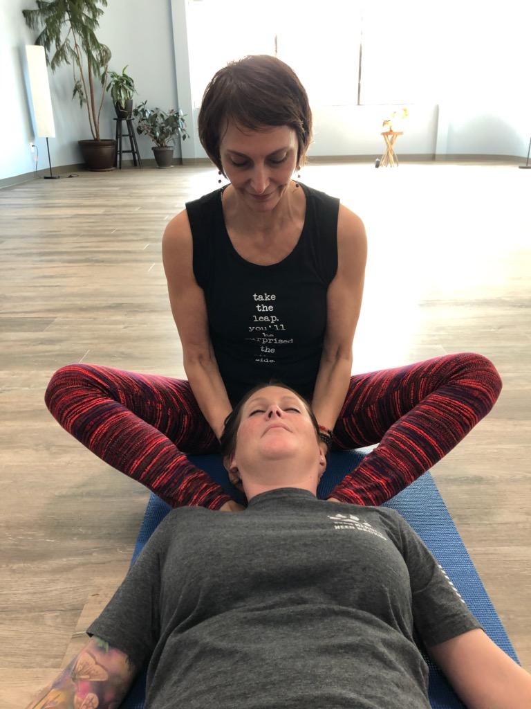 Holly Schramm lengthens woman's neck in savasana.